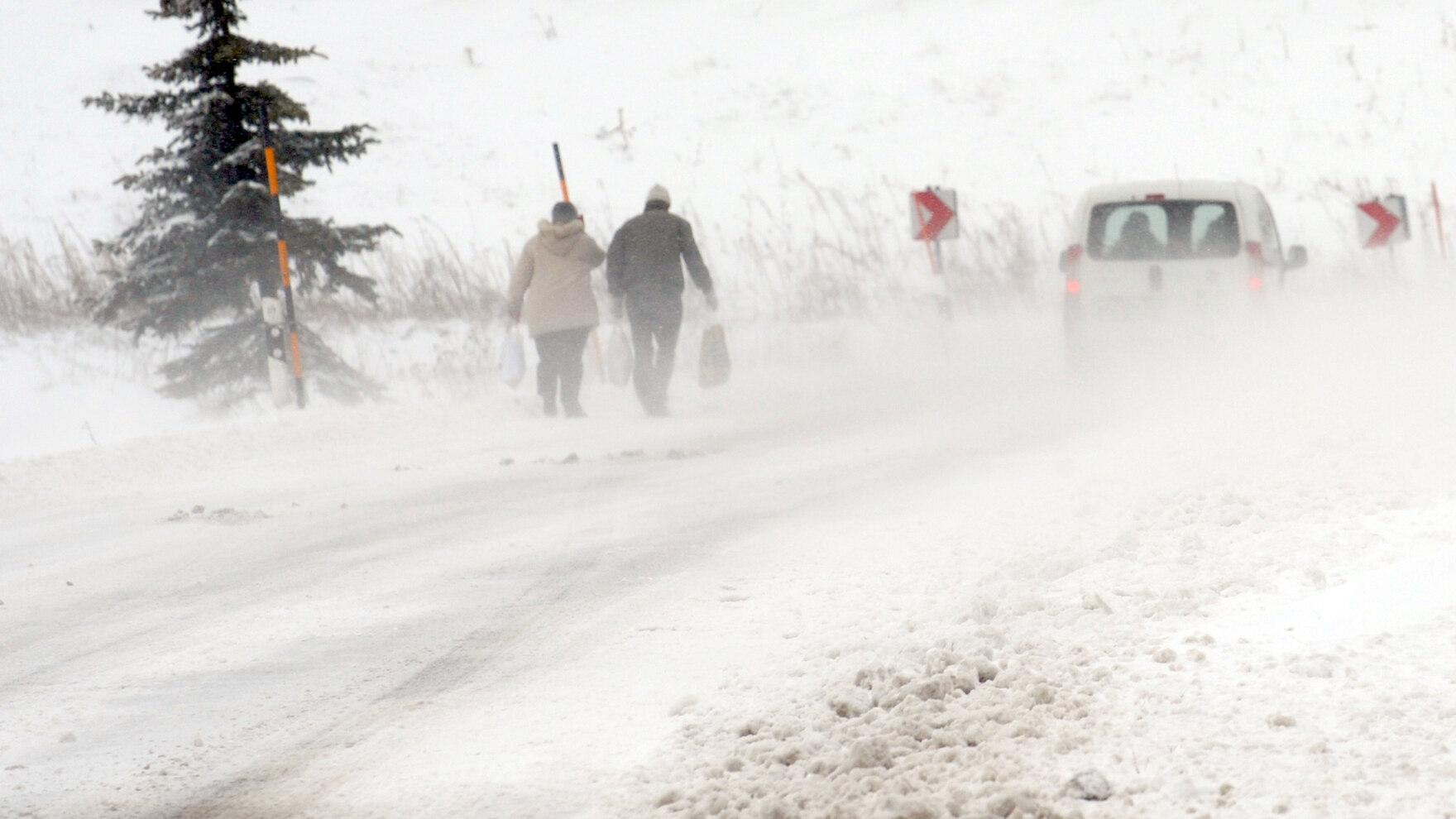 Menschen laufen in einem Wintersturm auf einer Straße.