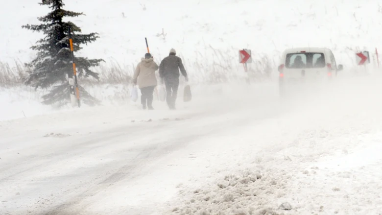 Menschen laufen in einem Wintersturm auf einer Straße.