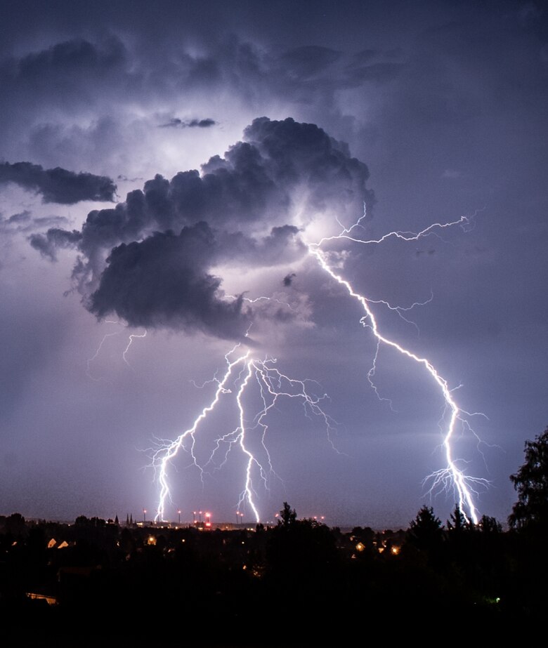 Ein Gewitter mit Blitzentladungen über einer Stadt.